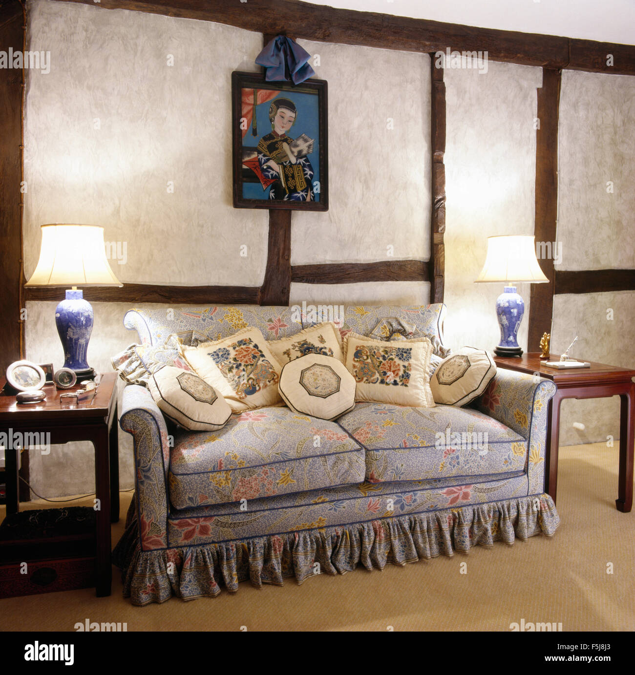 Blu pallido motivi floreali divani accatastati con cuscini in uno degli anni ottanta la stanza di seduta con parete esposta travi Foto Stock
