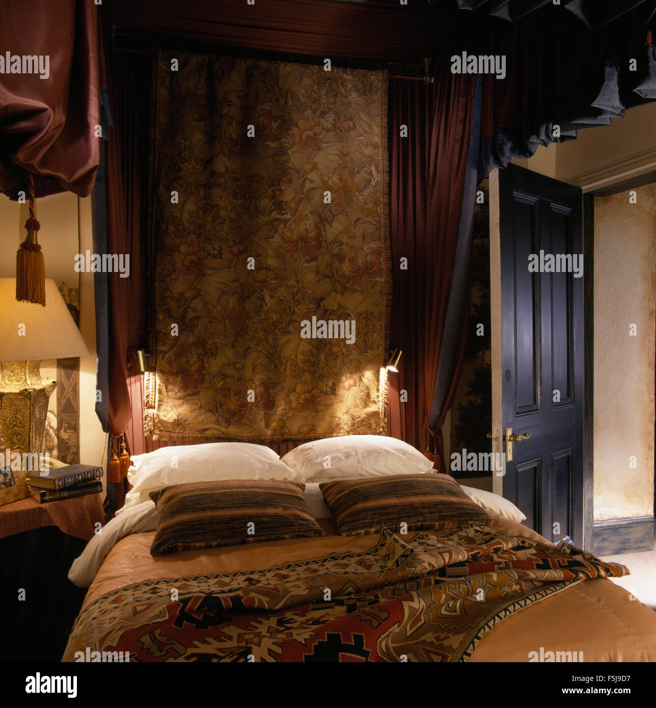 Ricca parete vintage appeso sopra metà letto tester con candida cuscini in una camera da letto degli anni ottanta Foto Stock