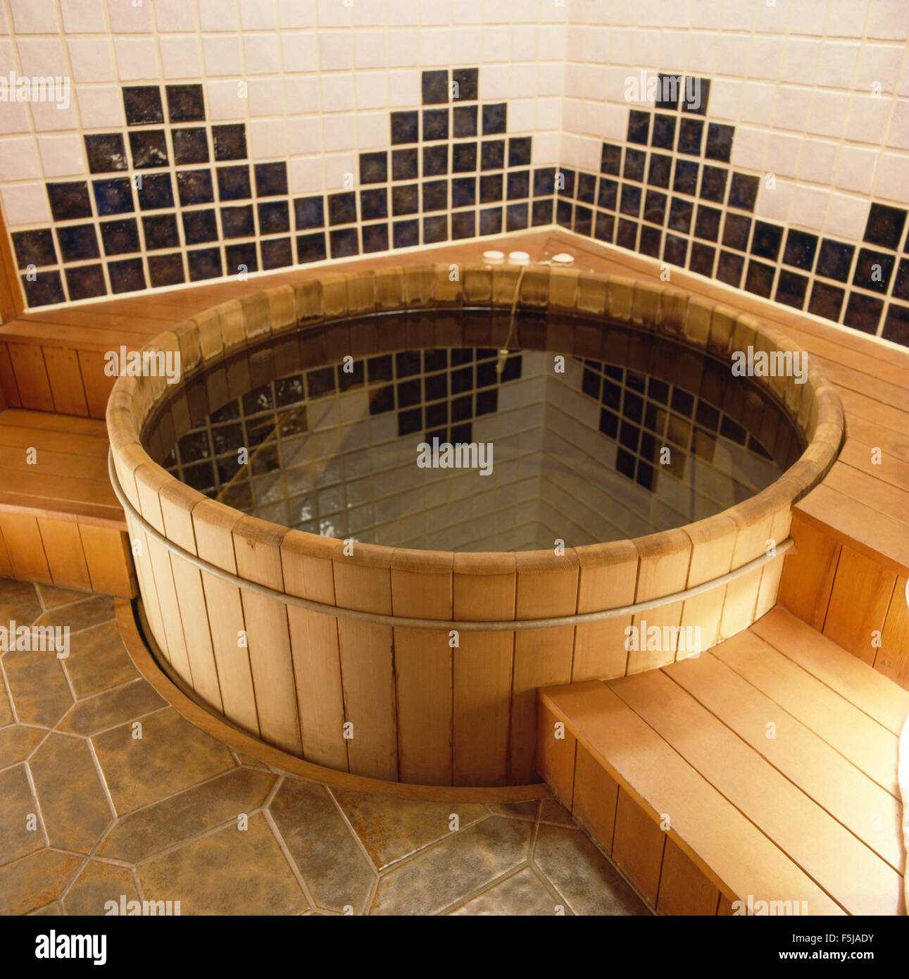 Gradini in legno intorno a una vasca idromassaggio nel bagno degli anni ottanta Foto Stock
