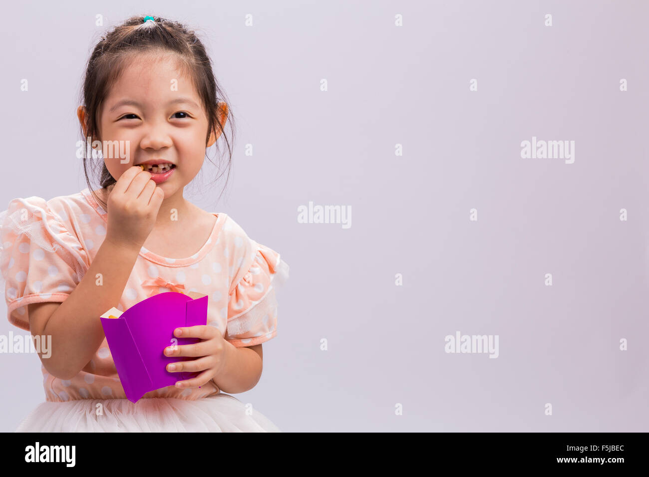 Bambina è mangiare patatine fritte con la felicità. Foto Stock