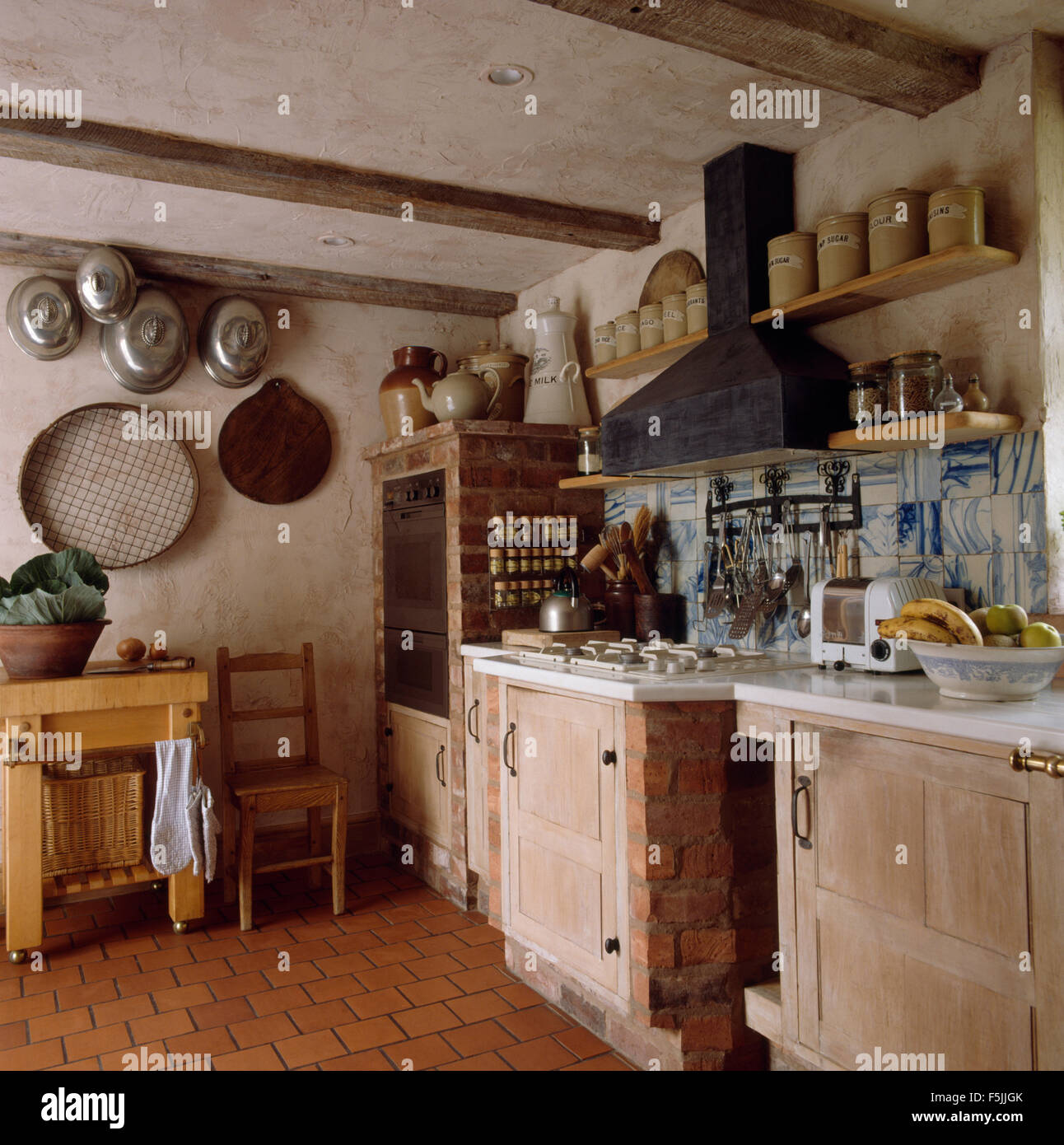 Storage di terracotta vasi su ripiani al di sopra del piano di cottura in una rustica cucina degli anni ottanta con carne di vintage copre e un grande vecchio crivello Foto Stock
