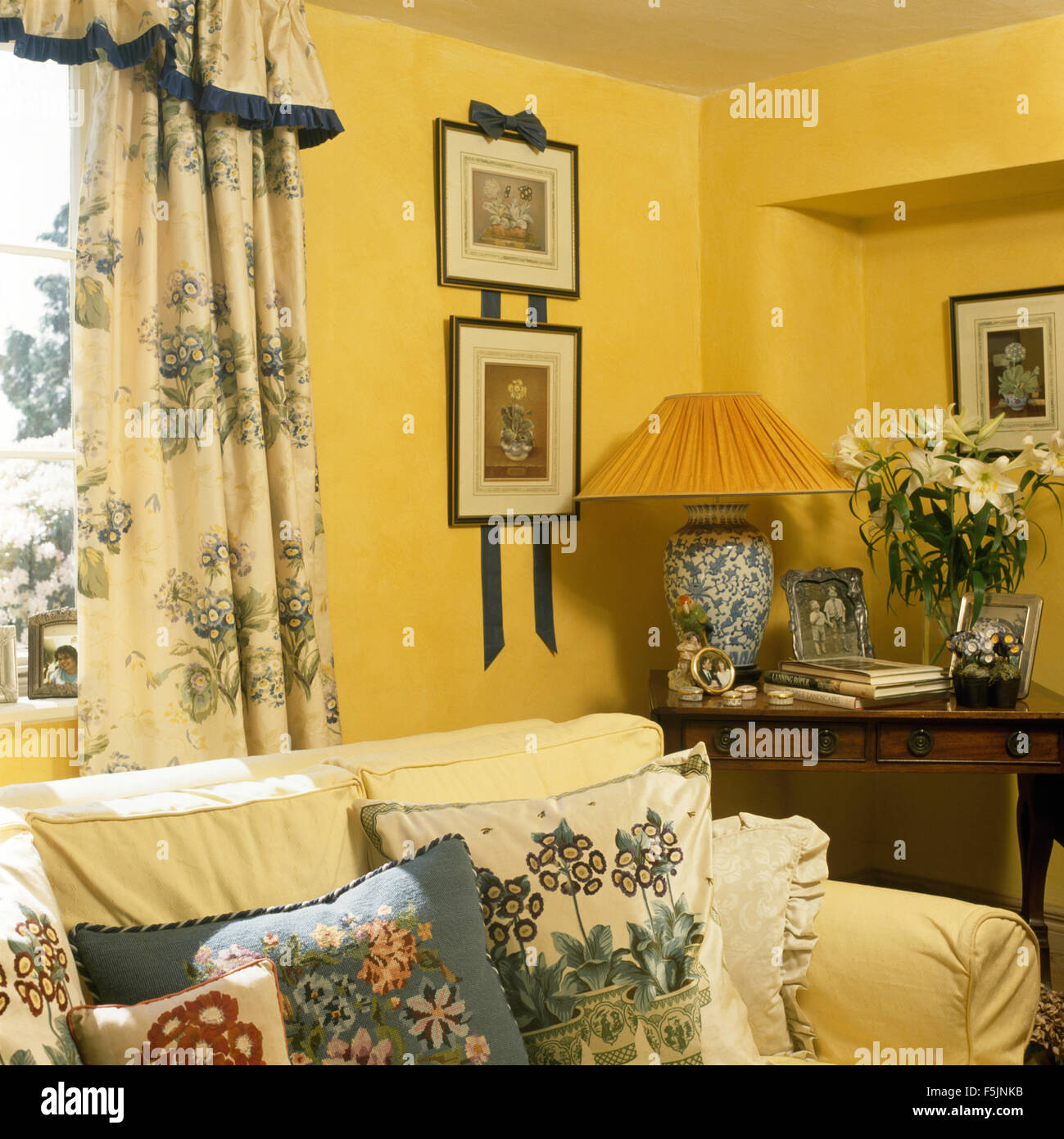 Primula padiglione auricolare themed le tende e cuscini e in un giallo degli anni novanta la stanza di seduta con le foto appese su nastri su parete Foto Stock