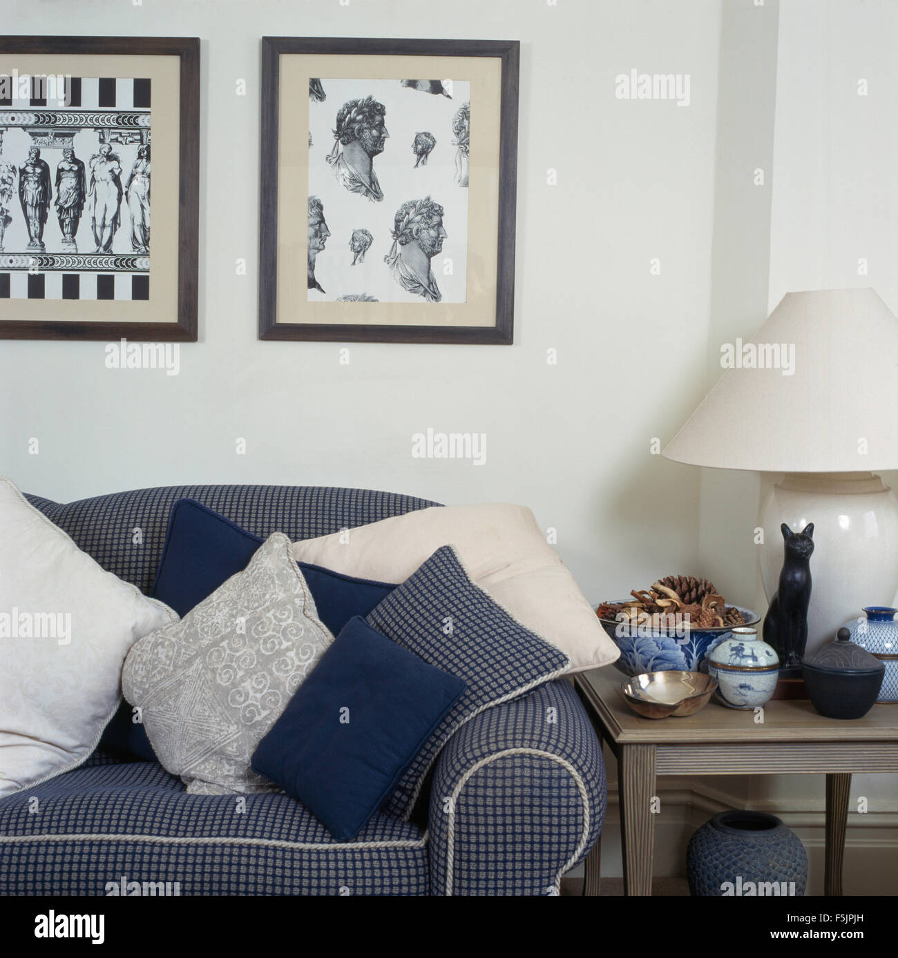 Nero+white neo-classico stampe incorniciate al di sopra di un blu selezionata divani accatastati con cuscini in una degli anni novanta soggiorno Foto Stock