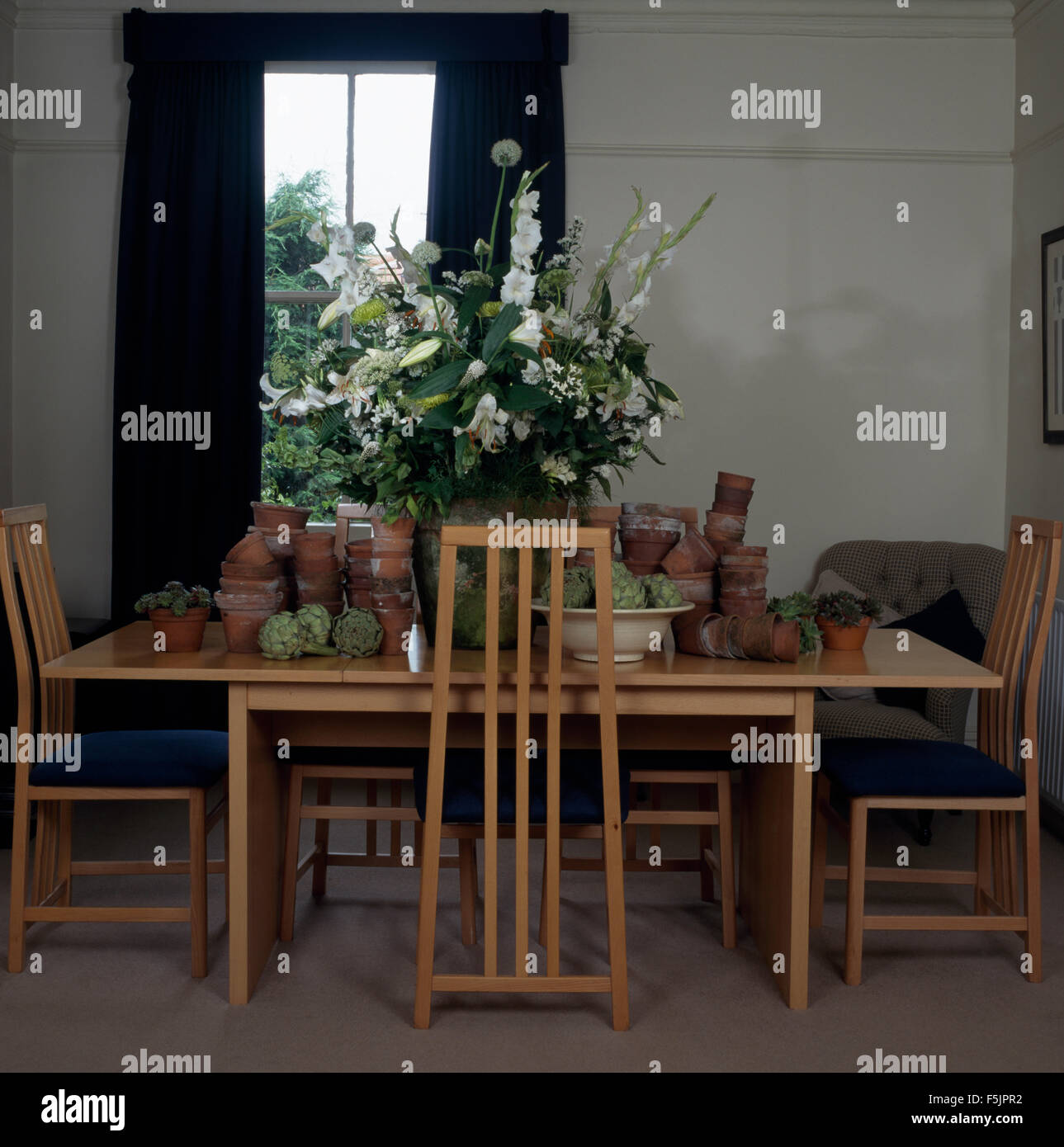 Tall torna bastone di legno indietro Sedie e tavola semplice con una collezione di vecchi vasi di terracotta e un bianco di composizione floreale Foto Stock