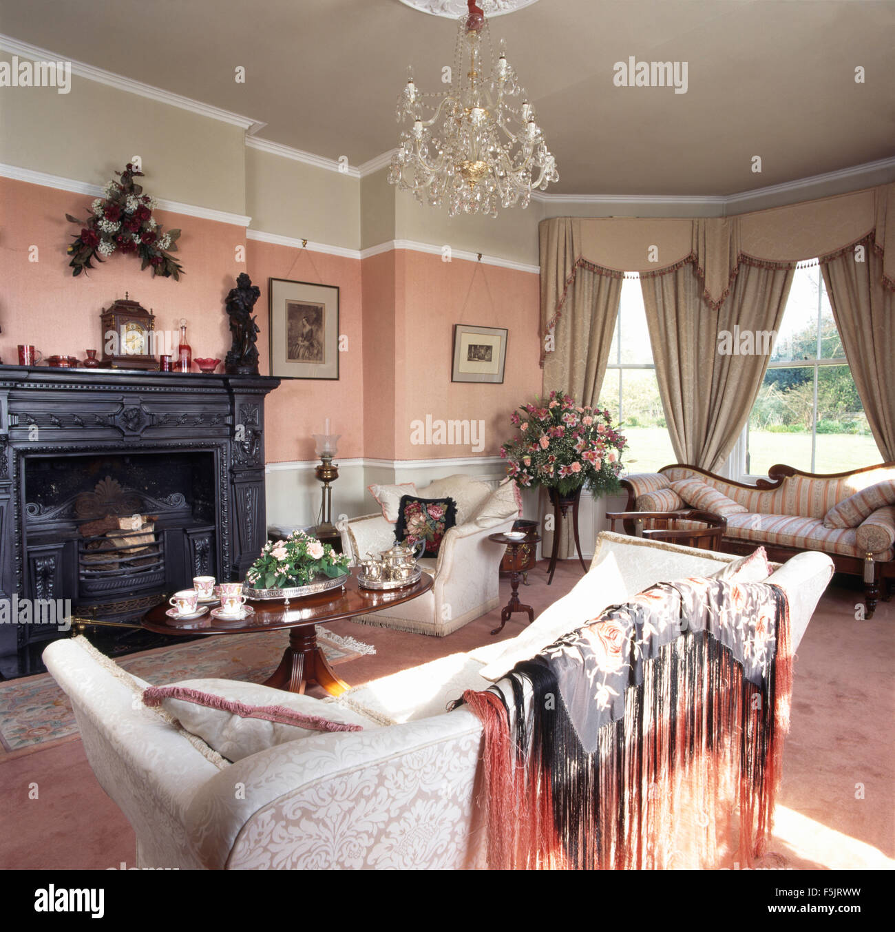 Vintage scialle frangiato drappeggiato sul divano in una rosa degli anni  novanta soggiorno con drappi beige e una ghisa camino Foto stock - Alamy
