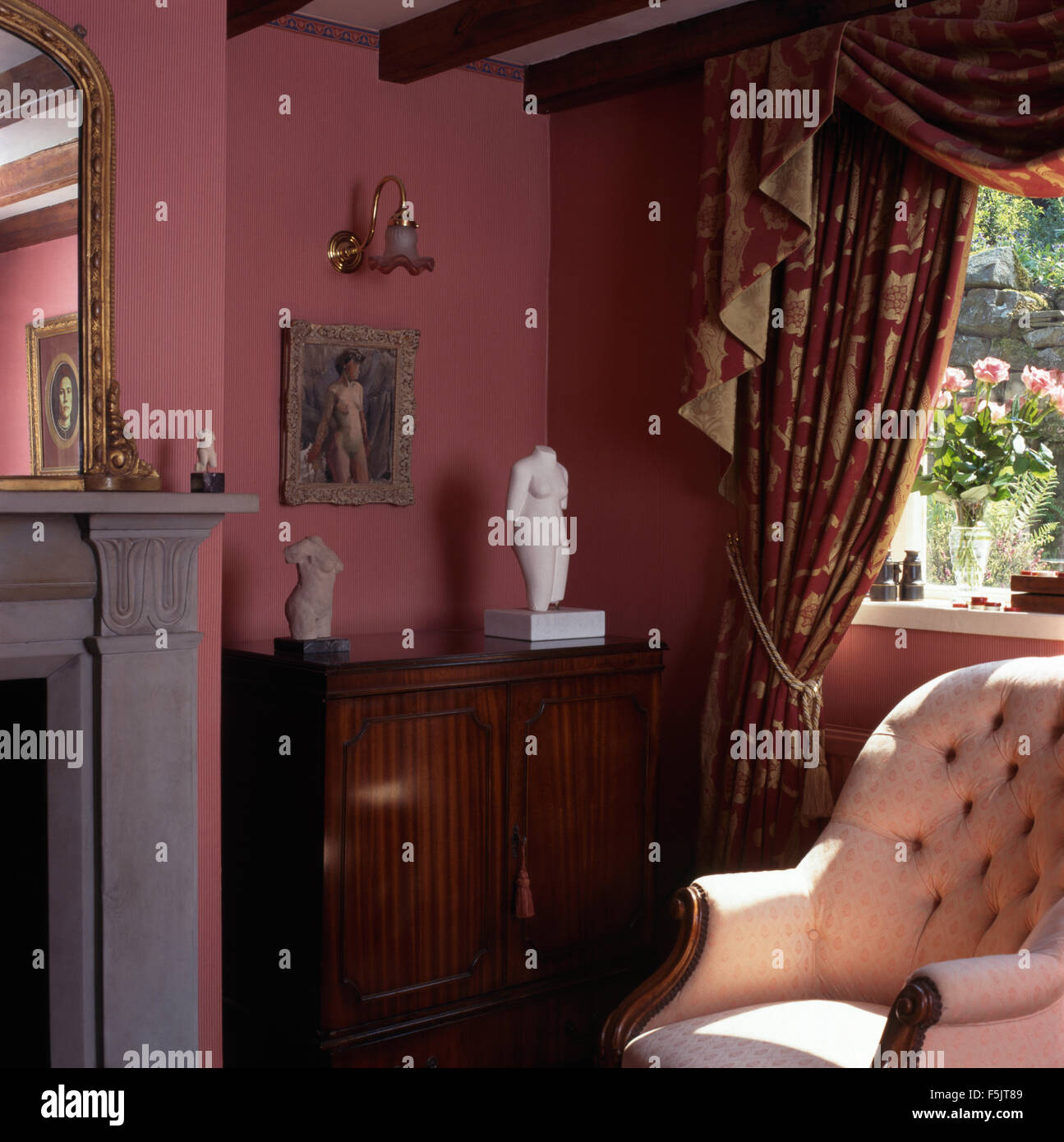 Crema pulsante vittoriano-indietro sedia sotto la finestra con swagged+tailed tende in rosa intenso degli anni novanta soggiorno Foto Stock