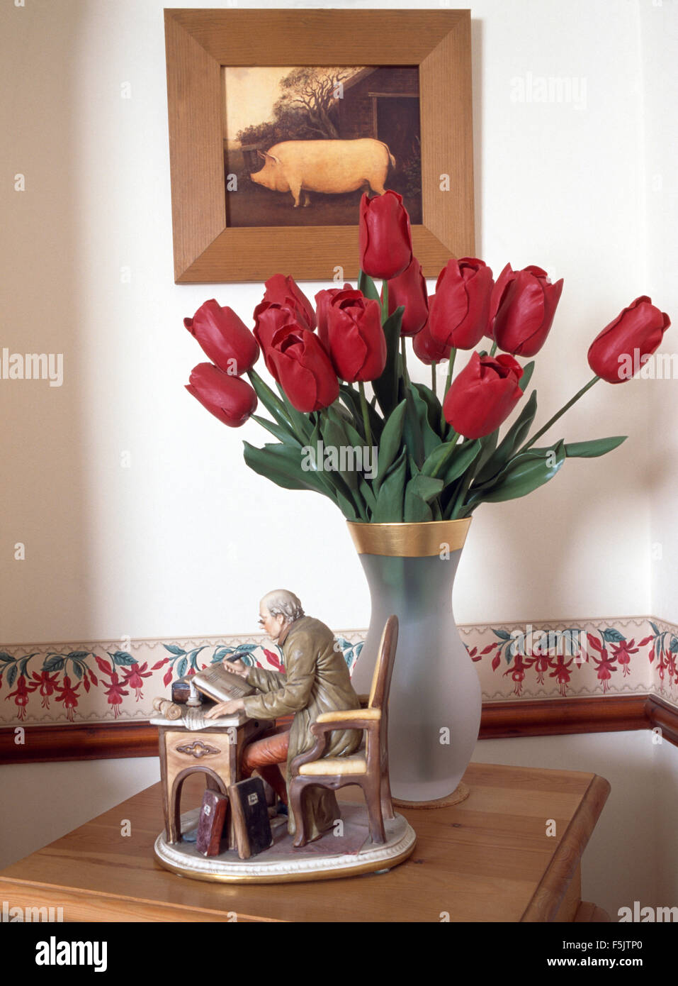 Immagine di un maiale al di sopra di un vaso di tulipani rossi e un annata di figurine di cina Foto Stock