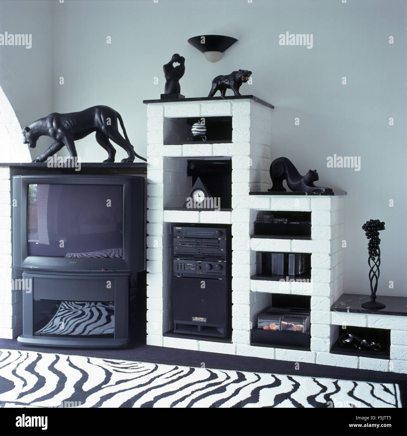 La televisione e la musica sul sistema verniciato bianco scaffalature in mattoni in uno degli anni novanta soggiorno Foto Stock