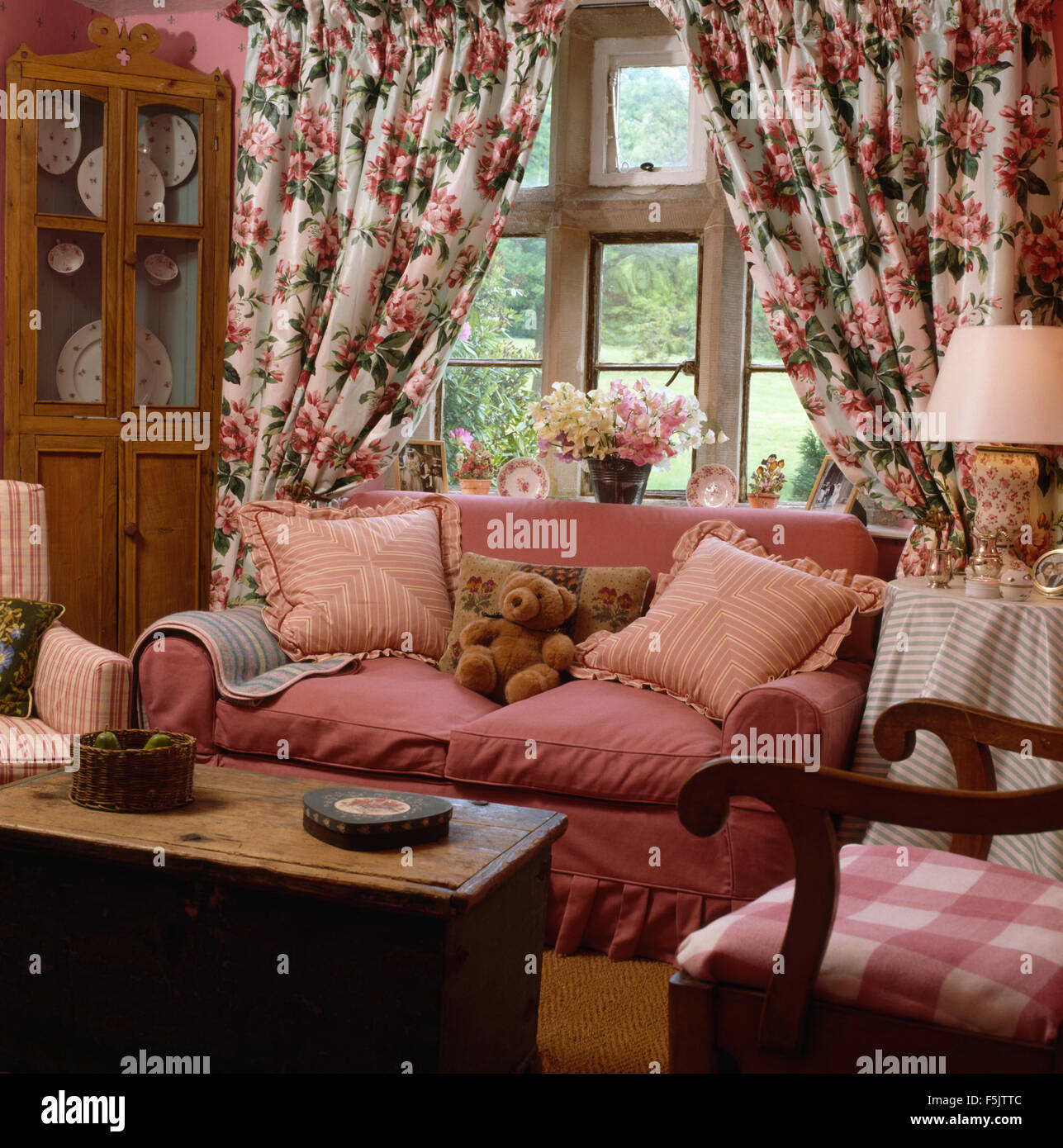 Tendaggi floreali sulla finestra dietro un divano rosa nel paese soggiorno  con un vecchio pino petto utilizzato come un tavolo da caffè Foto stock -  Alamy