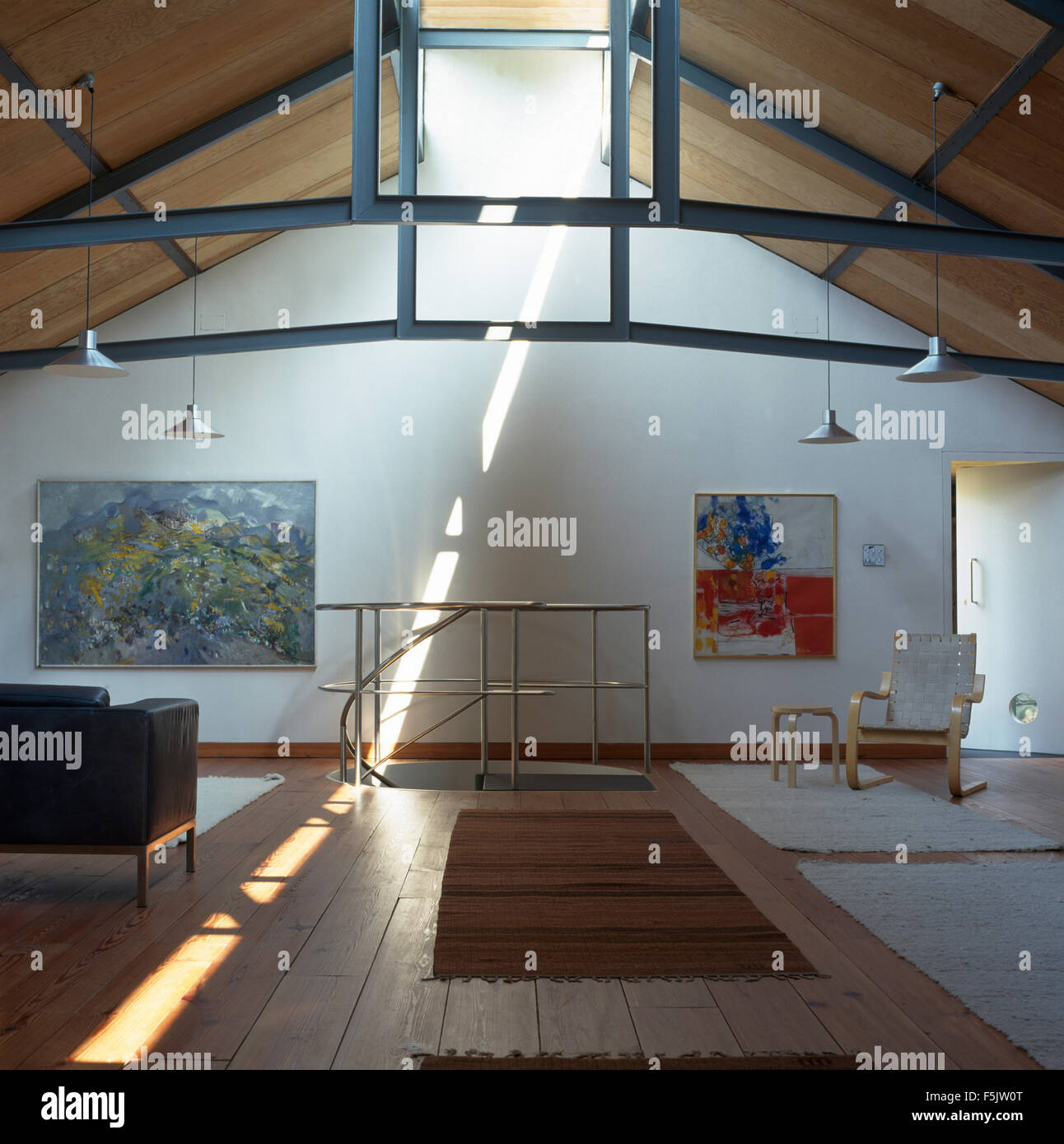 Metà secolo mobili in un soggiorno in un paese di conversione loft con tappeti sul pavimento in legno Foto Stock