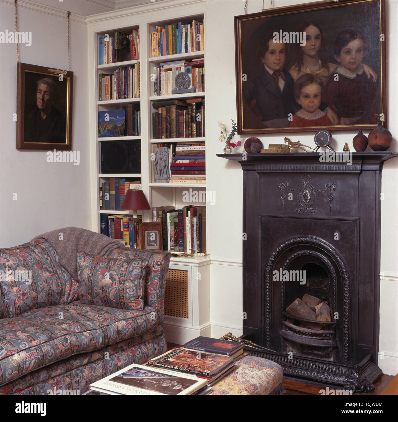 Pittura a olio sopra i piccoli ghisa camino ho degli anni novanta un soggiorno con costruito in libreria e un divano modellato Foto Stock
