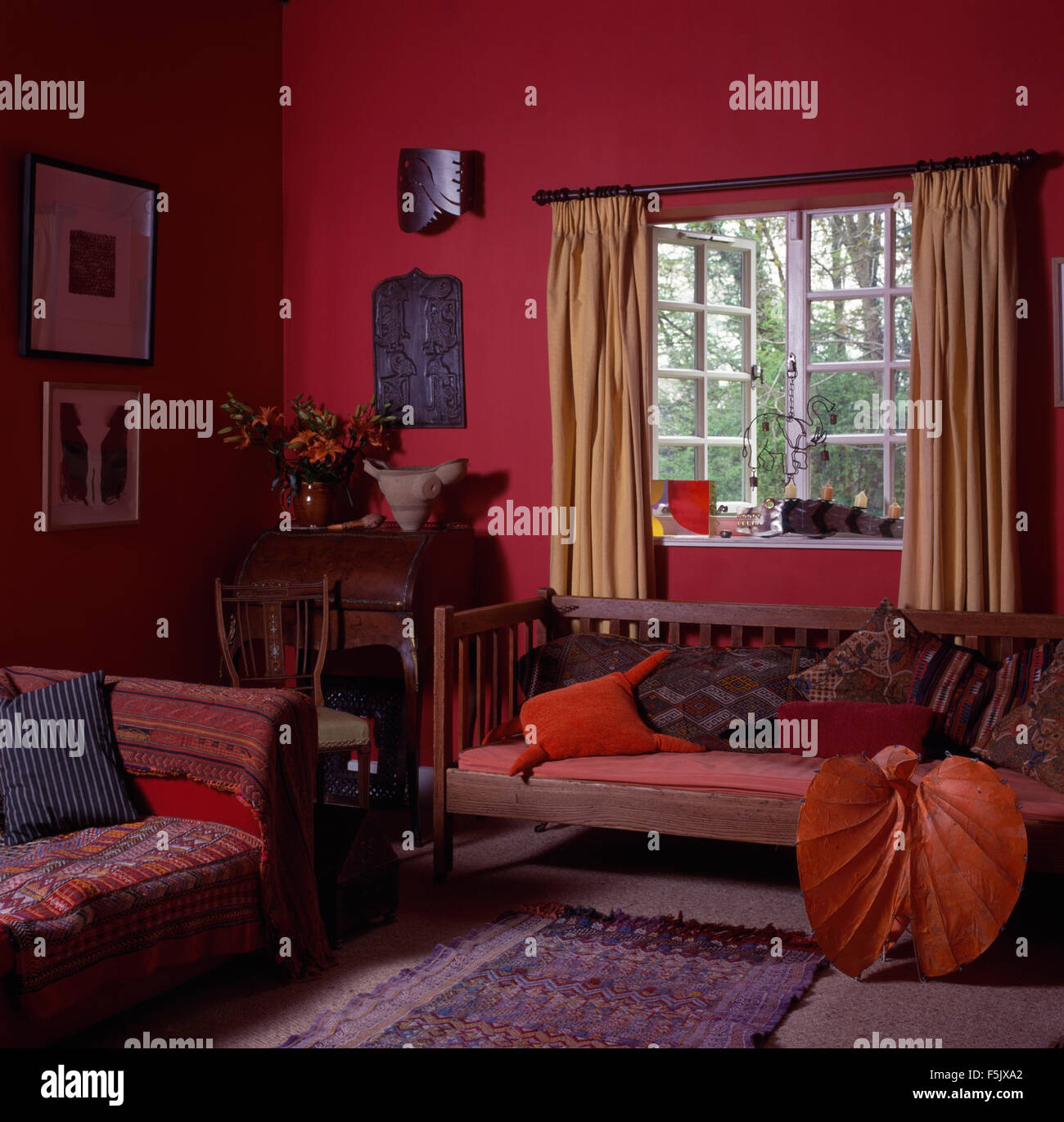 Cuscini su legno di stabilirsi in un vecchio rosso scuro stile economy la stanza di seduta con motivi getta sul divano Foto Stock