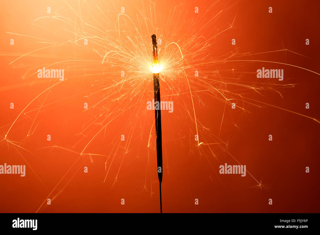 Burning sparkler davanti a uno sfondo arancione Foto Stock