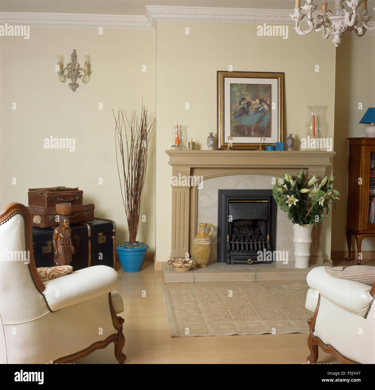 La crema di poltrone e caminetto in pietra in una nuova costruzione soggiorno con una foto su una pietra mantelpiece Foto Stock