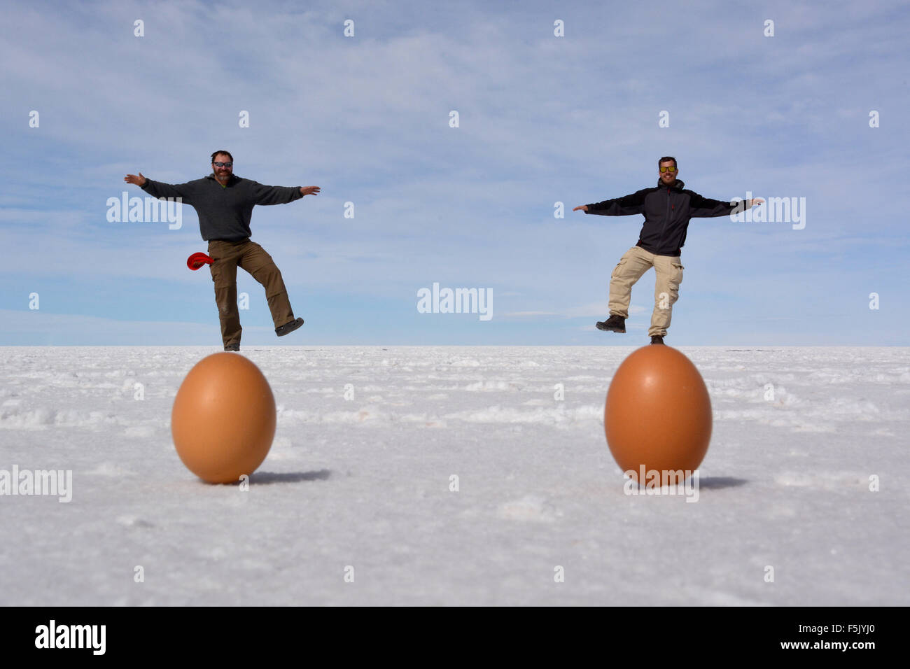 Illusione ottica, due uomini stavano in piedi sulle uova, Salt Lake Salar de Uyuni, Bolivia Foto Stock