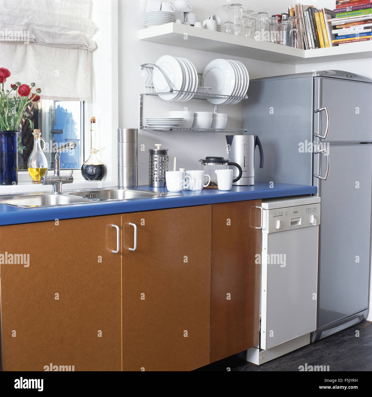 Piccola lavastoviglie e frigorifero con congelatore degli anni novanta in cucina con un piano di lavoro di colore blu Foto Stock