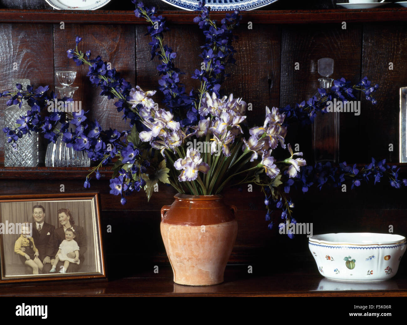 Close-up di un ripiano vaso di delphiniums blu e il vecchio nero+fotografia in bianco Foto Stock