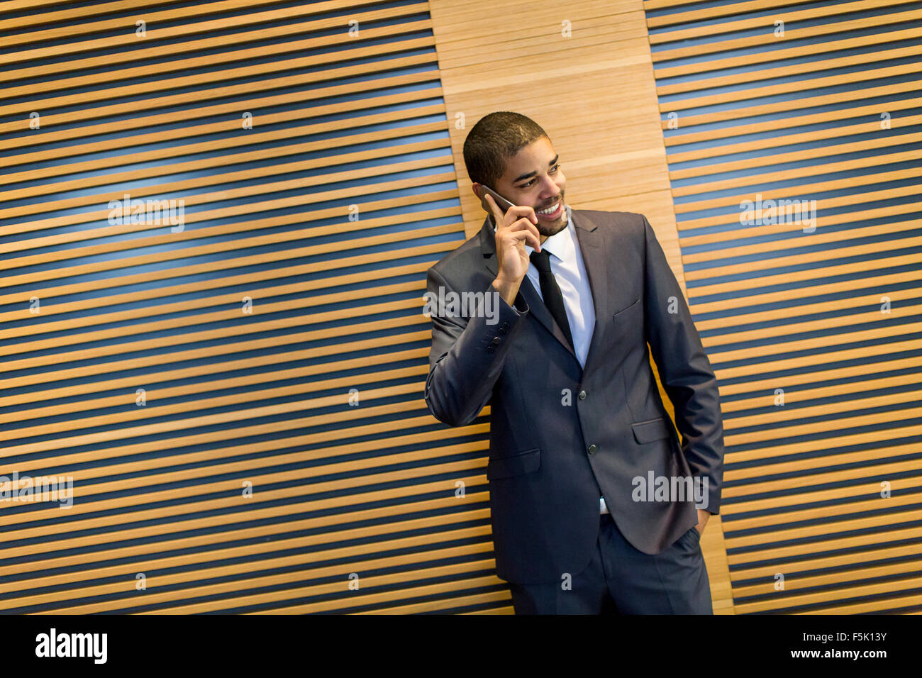 Bel giovane uomo nero con il cellulare in ufficio Foto Stock