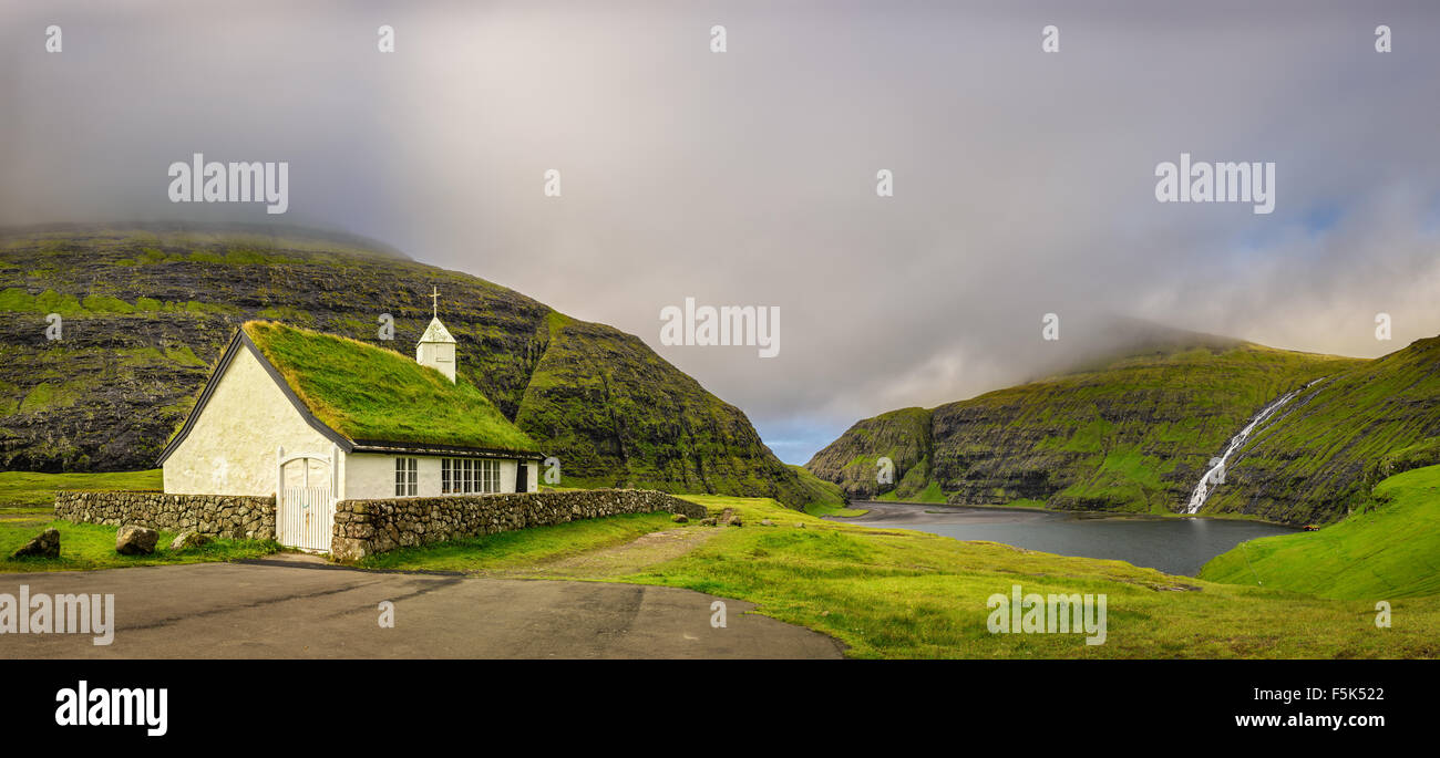 Panorama di una piccola chiesa in Saksun, nelle vicinanze del lago e di una cascata che si trova sull'isola di Streymoy, Isole Faerøer, Danimarca Foto Stock