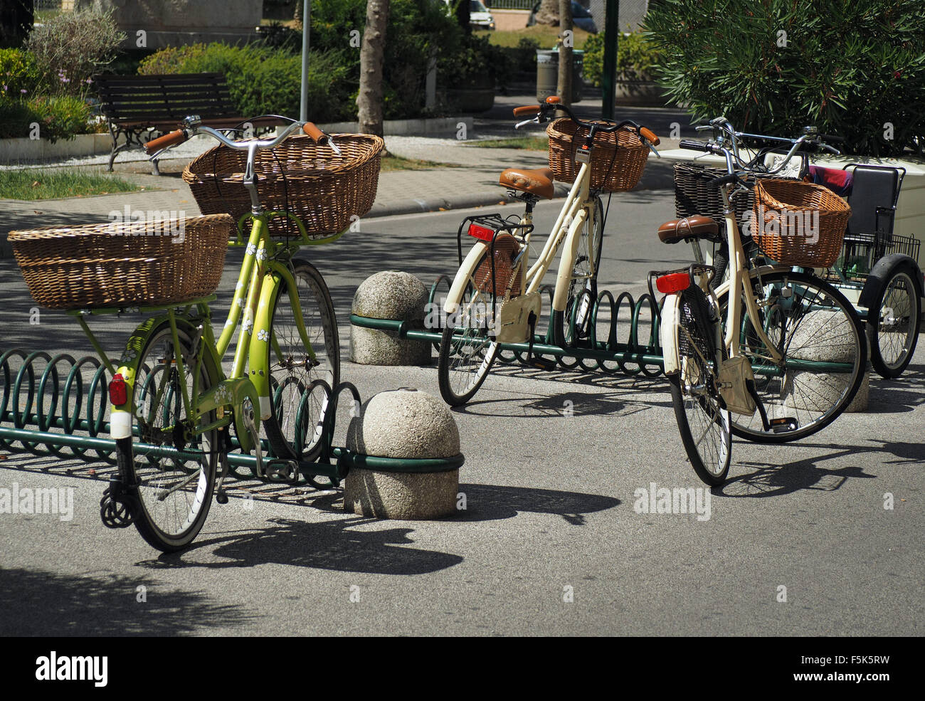 Tre biciclette con gerle parcheggiato nel rack spiralato fornito in un italiano off street park impostato in corrispondenza di angoli jaunty Foto Stock