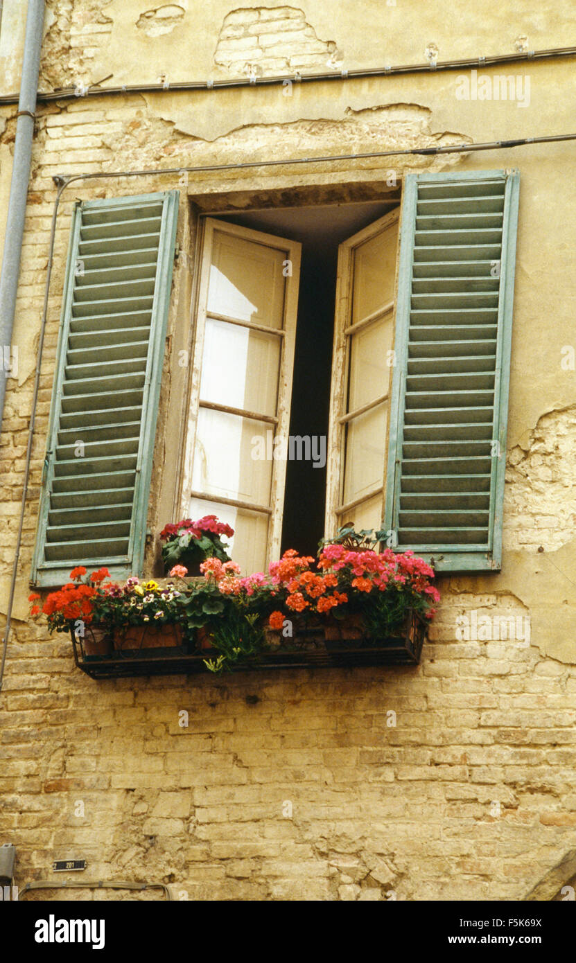 L'esterno di una casa francese con il rosso dei gerani nella finestra casella sotto la finestra con persiane colorate Foto Stock