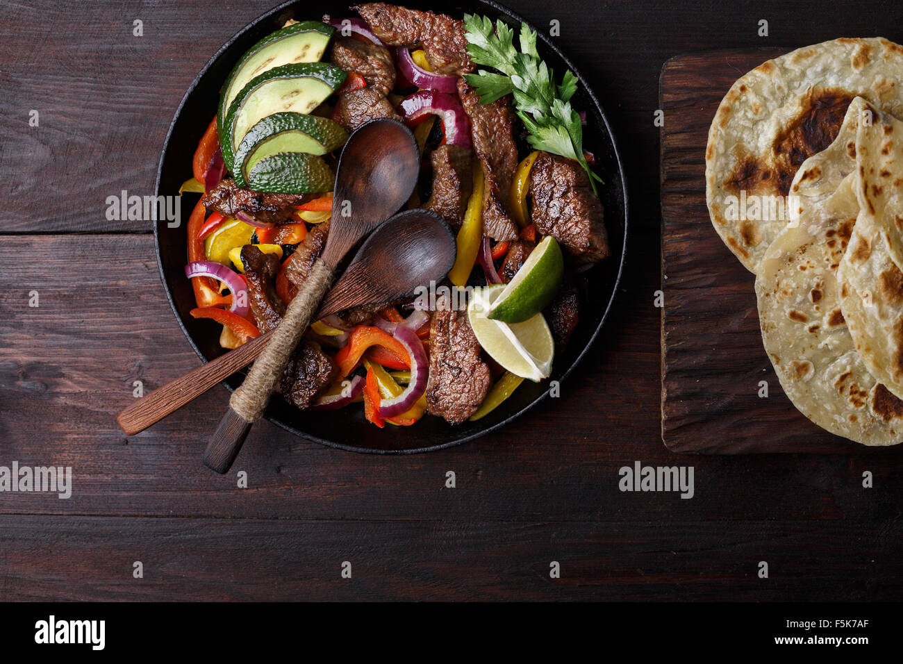Carni bovine fajita con peperoni. Tortillas, avocado, salsa servita con grigliate di carne di manzo e verdure in padella. Tex-mex cuisine Foto Stock