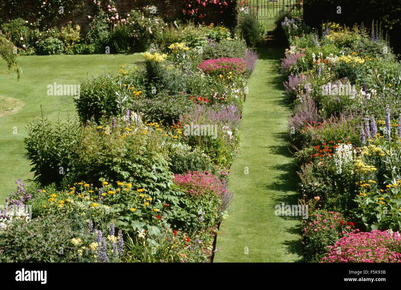 Perennials colorato in una vasta gamma di bordi laterali o di un percorso di erba di un cancello di ferro in un paese grande giardino in estate Foto Stock