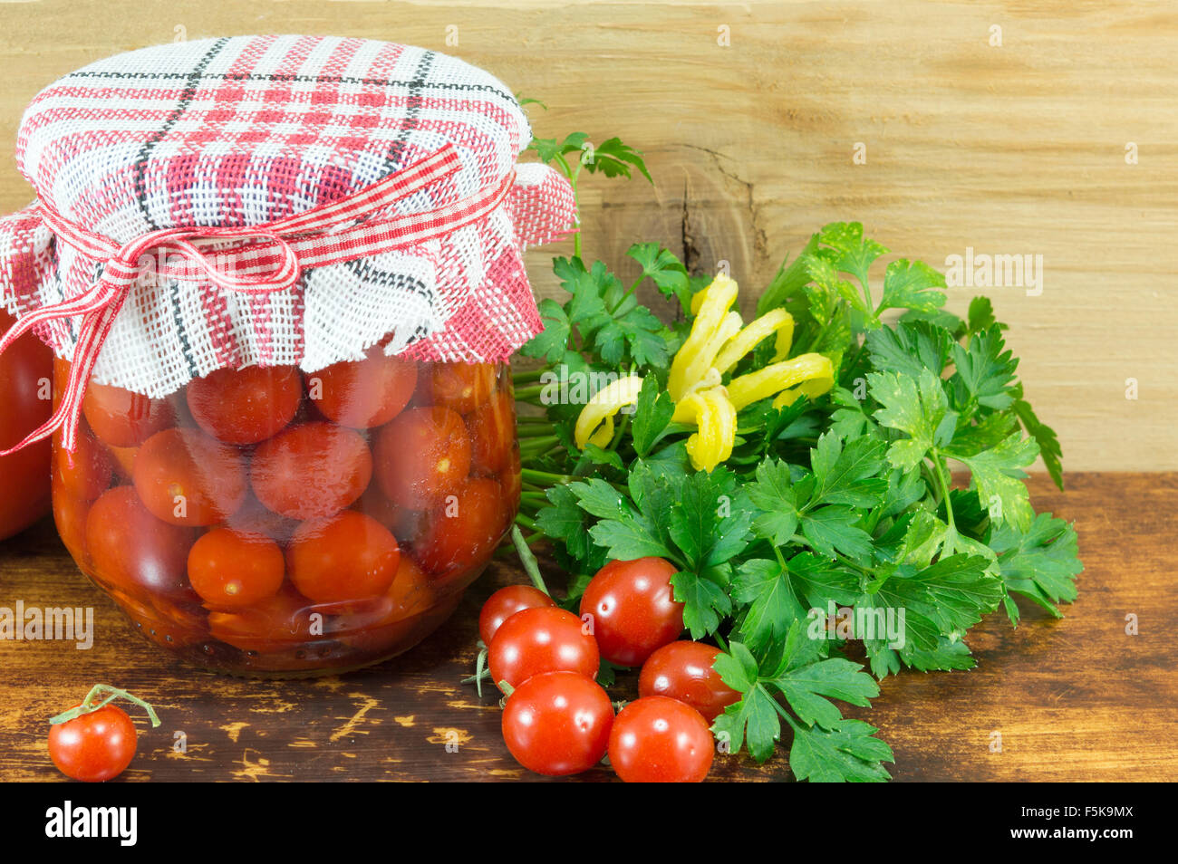 Barattolo di ketchup fatti in casa e pomodoro ciliegino accanto a freschi pomodori ciliegia su sfondo di legno Foto Stock