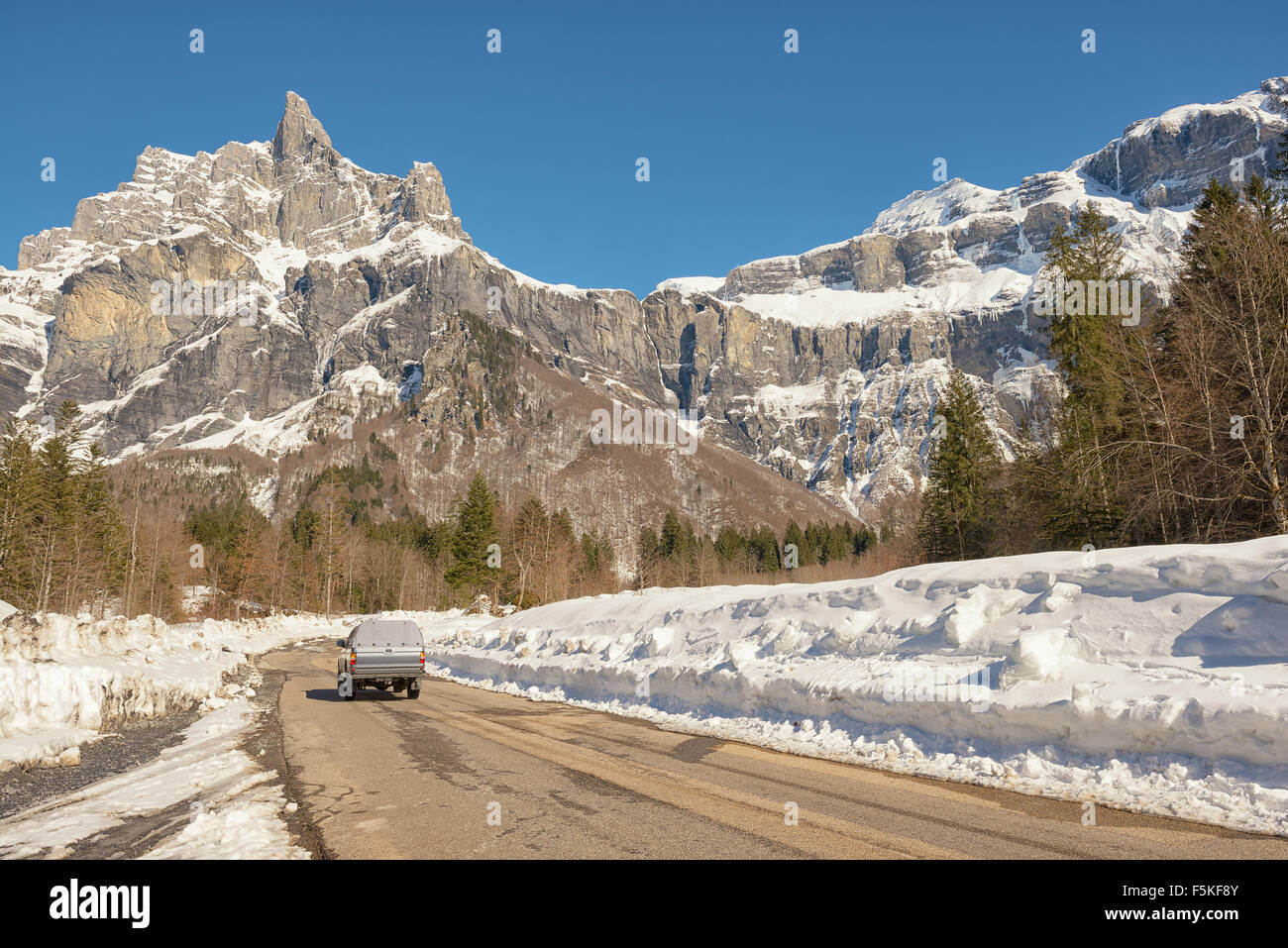 Un pick up truck guida su una strada innevata che conduce a una montagna Foto Stock