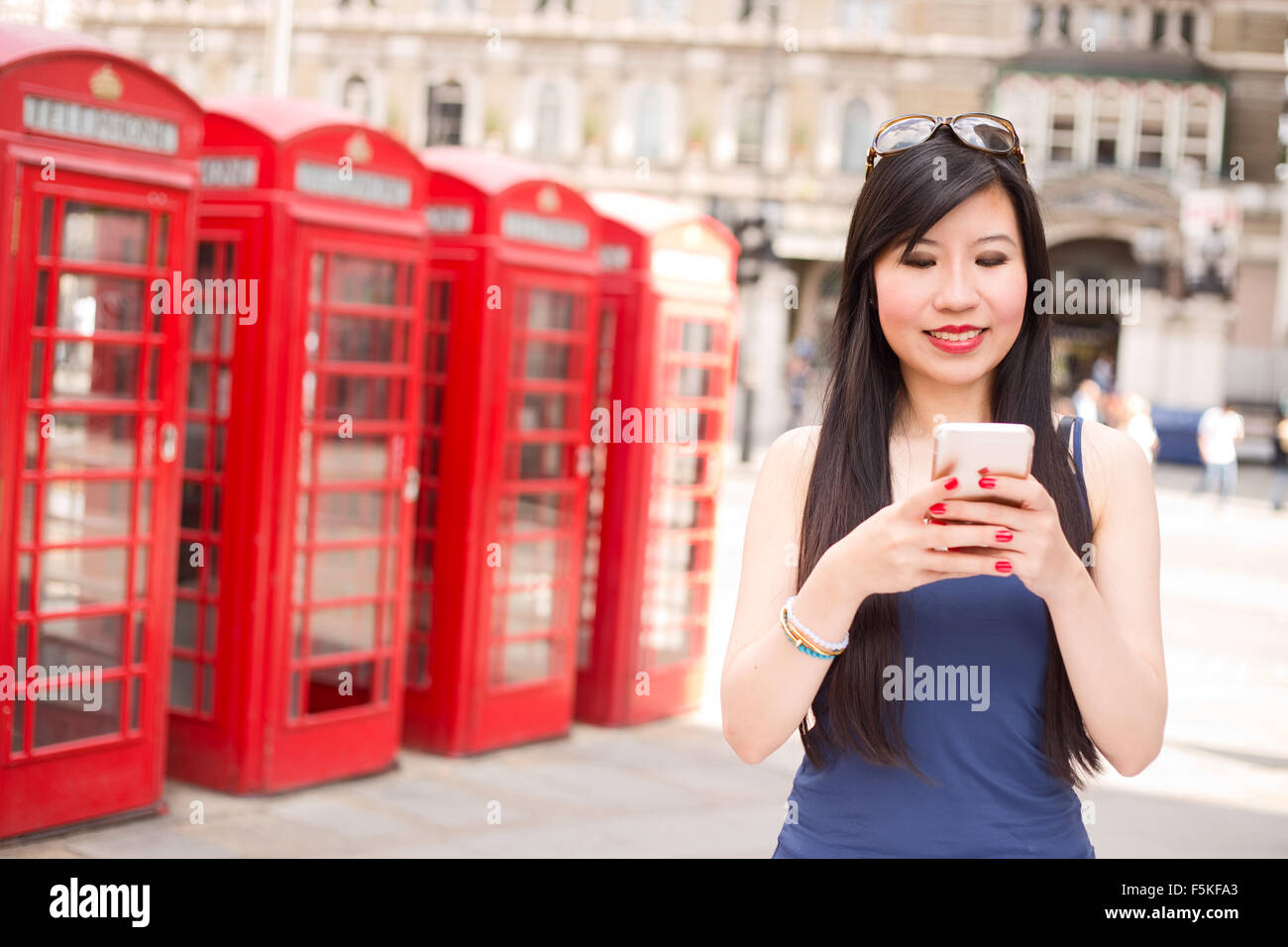 Donna giapponese inviando un sms sul suo telefono cellulare in Londra Foto Stock
