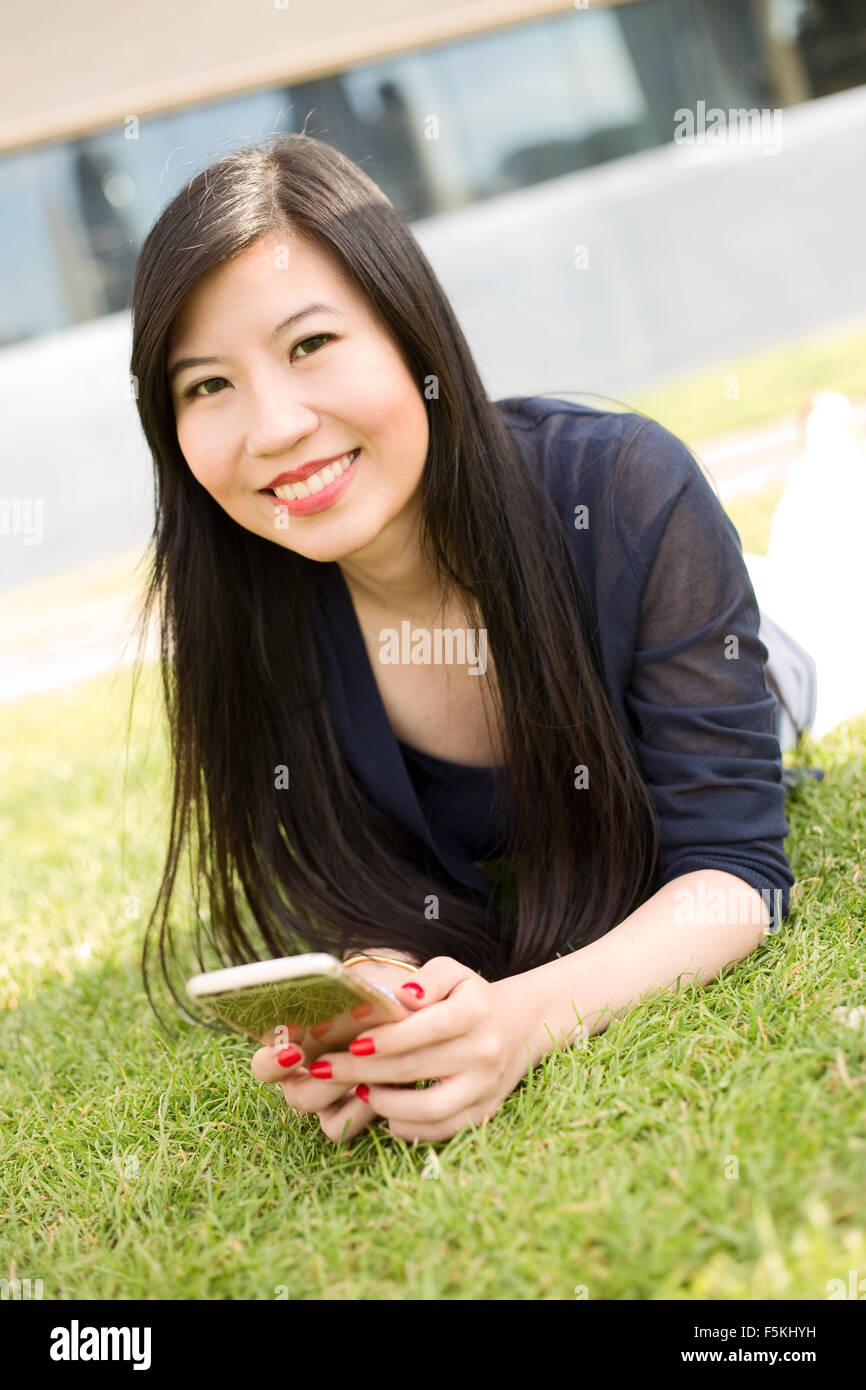 Ragazza giapponese nel parco mentre tiene il suo telefono cellulare Foto Stock