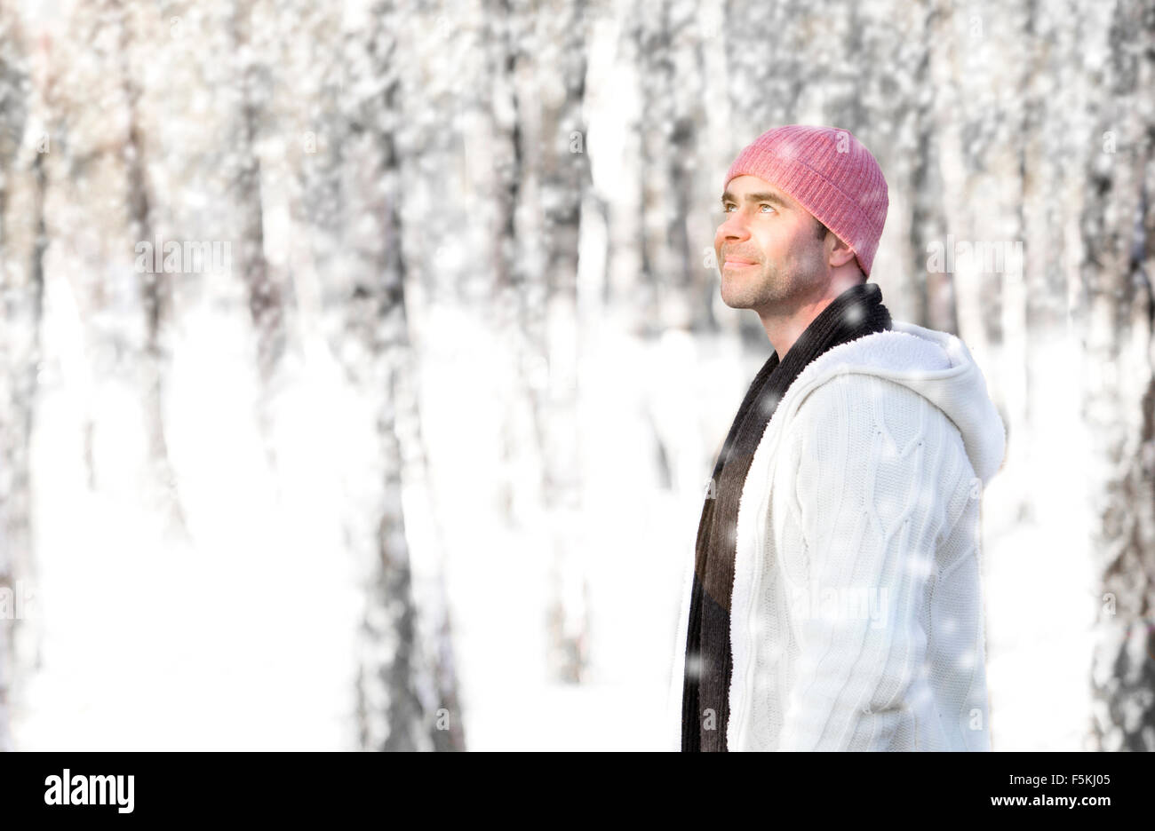 Uomo che cammina nella foresta nella neve e sorrisi Foto Stock