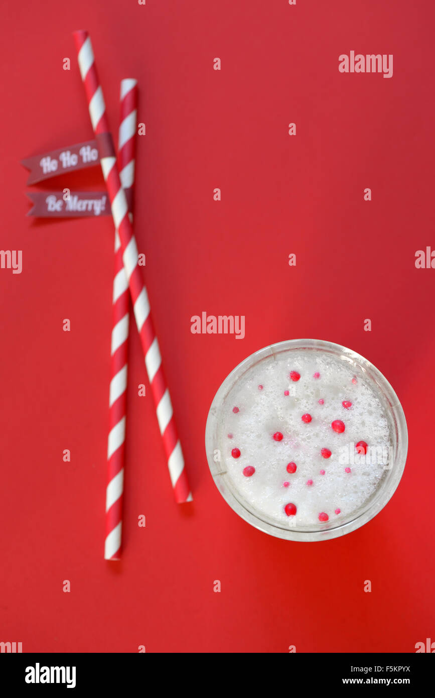 Un bicchiere di latte e Cannucce di carta su sfondo rosso Foto Stock