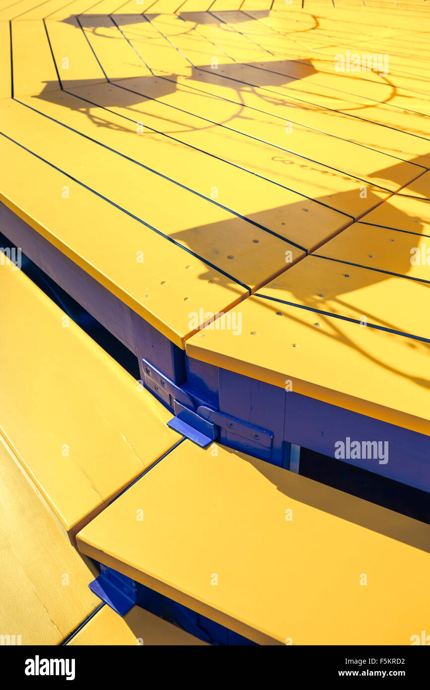 Dettaglio del giallo scale di legno di una giostra di oscillazione e le ombre delle sedi di rotazione sulle tavole / gioco di ombre a scale Foto Stock