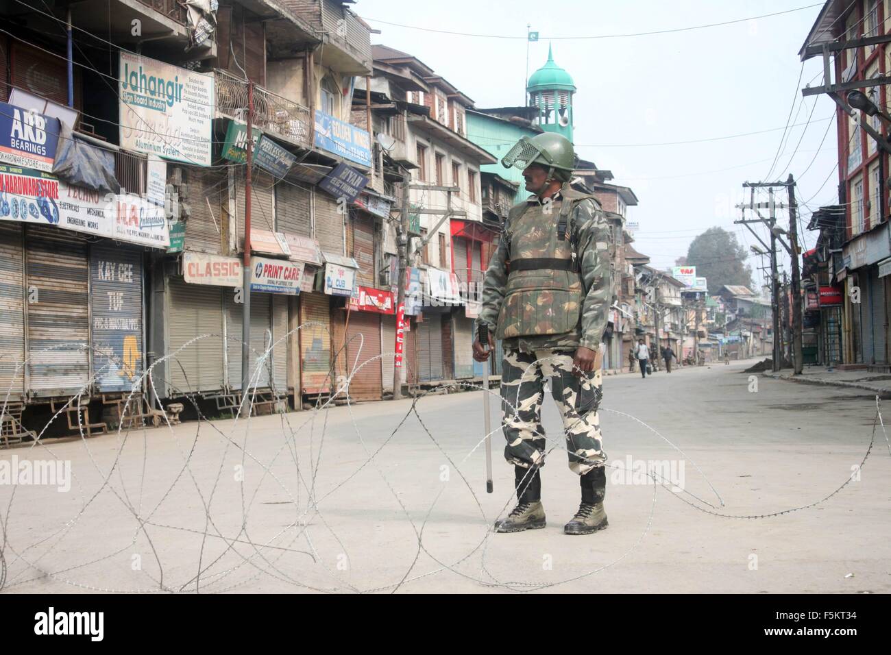 Poliziotto indiano si erge nei pressi di filo spinato durante il coprifuoco a Srinagar. Foto Stock