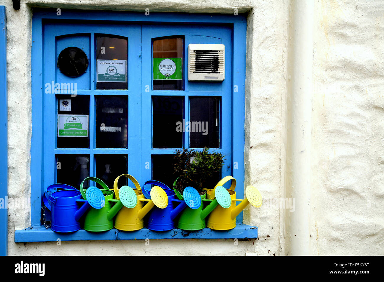 Innaffiatoi sul davanzale della finestra di un cafe finestra della cucina a Mevagissey in Cornovaglia, UK. Foto Stock