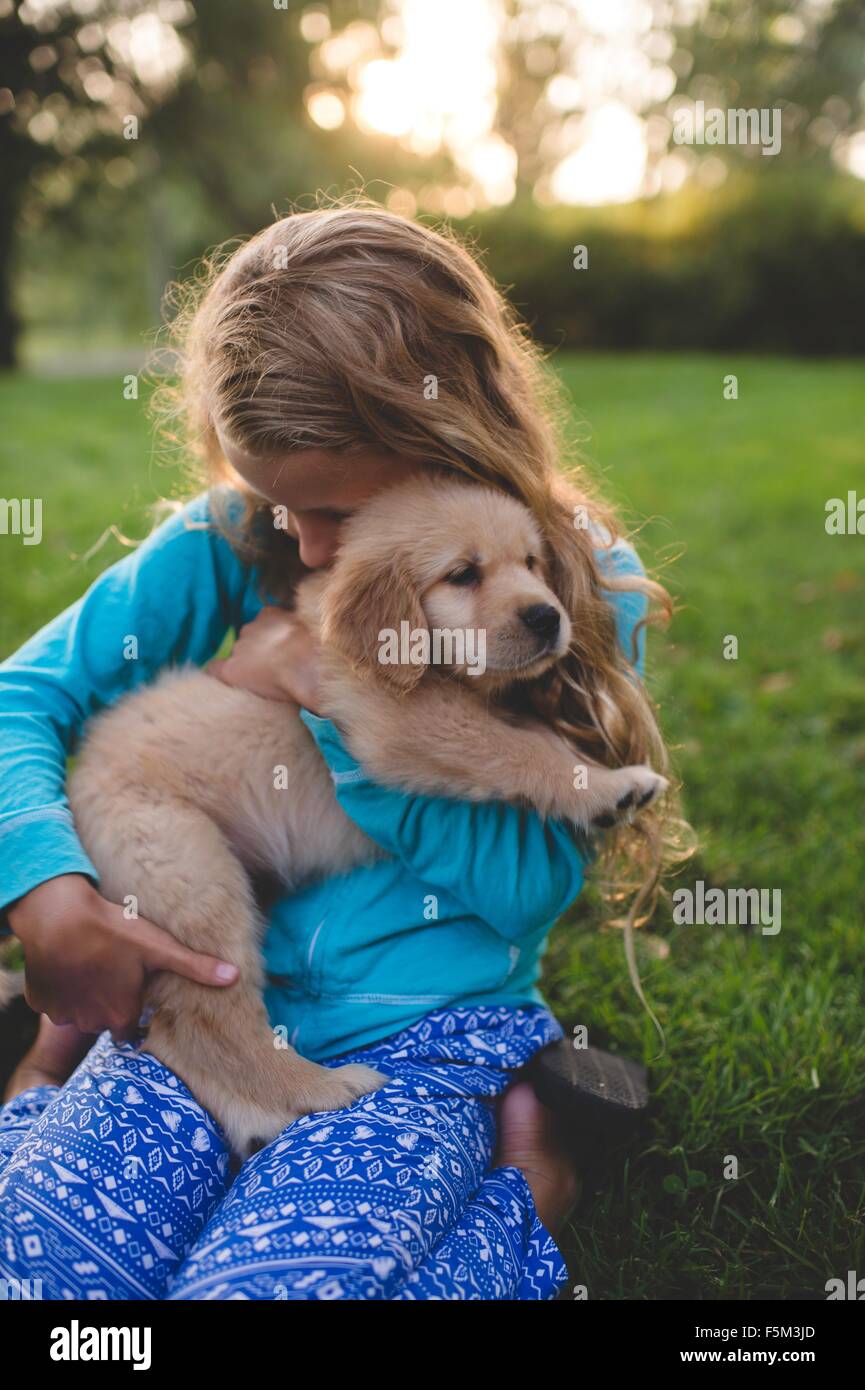 Ragazza abbracciando puppy in giardino al tramonto Foto Stock