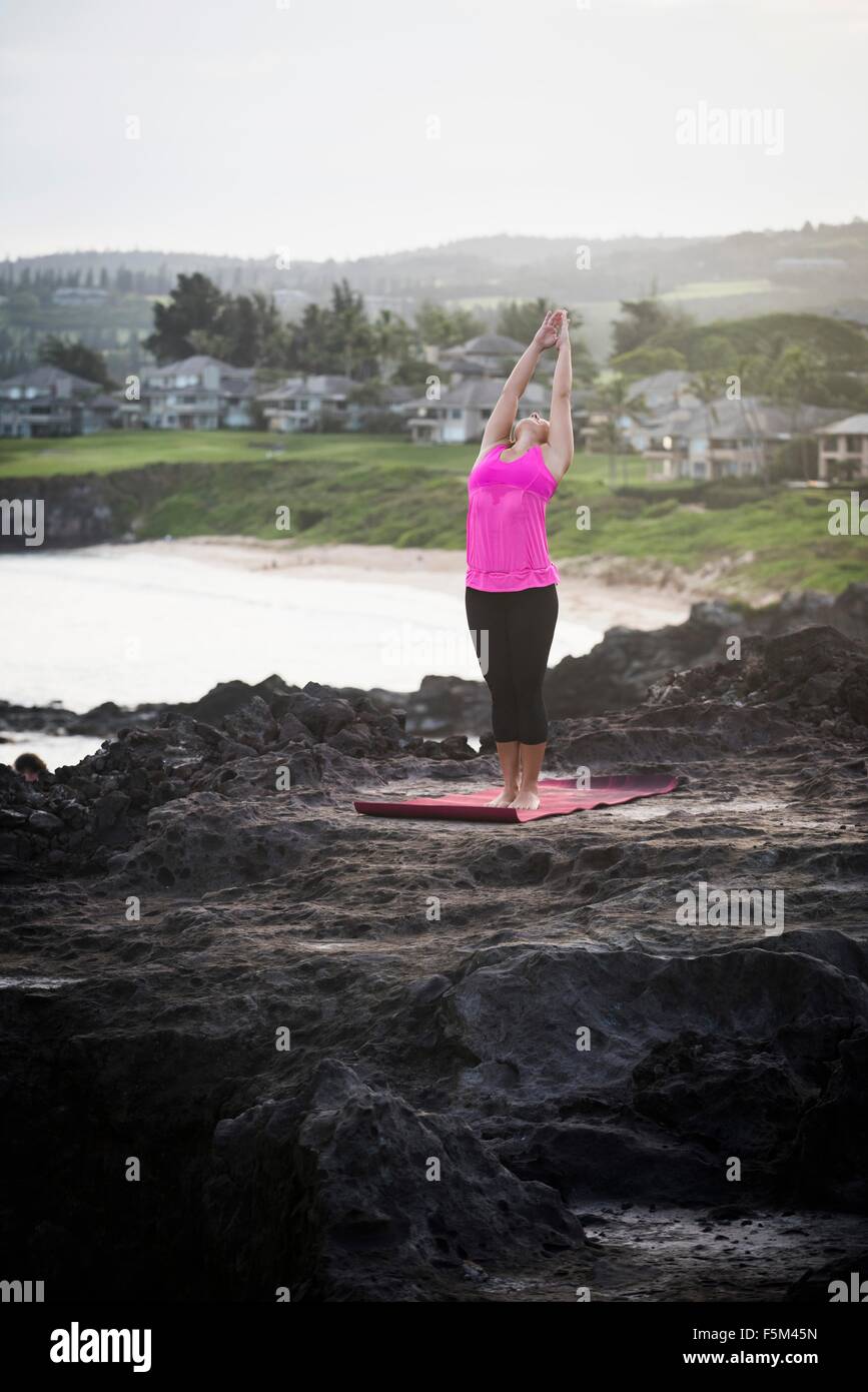 La donna a costa la pratica dello yoga con le braccia sollevate, punto Hawea, Maui, Hawaii, STATI UNITI D'AMERICA Foto Stock