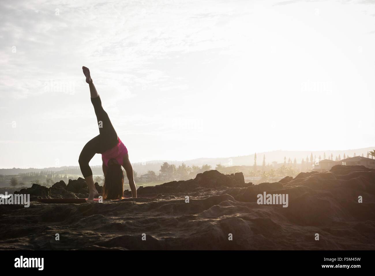 La donna a costa pratica capovolte Yoga asana Hawea punto, Maui, Hawaii, STATI UNITI D'AMERICA Foto Stock
