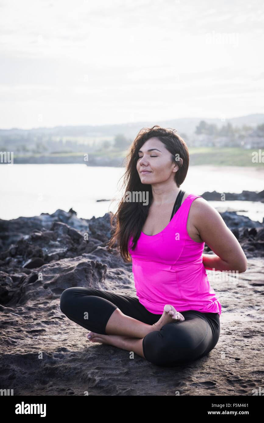 La donna a costa la pratica dello yoga nella posizione del loto, punto Hawea, Maui, Hawaii, STATI UNITI D'AMERICA Foto Stock