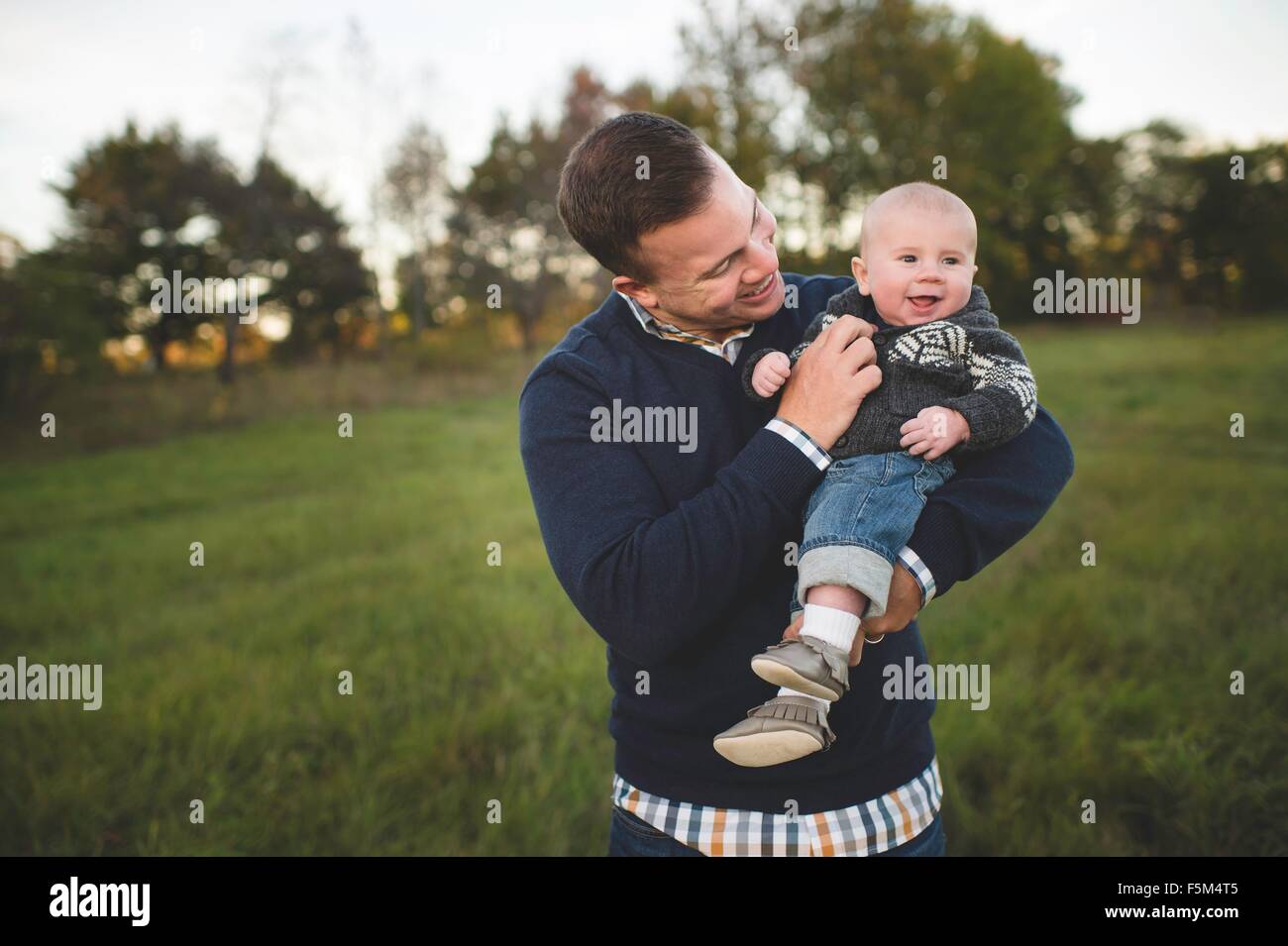 Metà uomo adulto bambino portando il figlio in campo Foto Stock