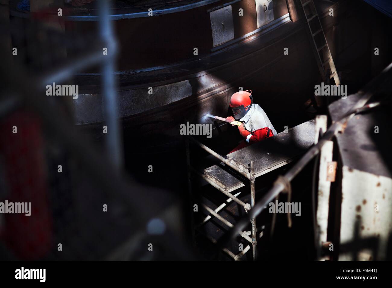 Lavoratore Pulizia barca con tubo flessibile ad alta pressione in cantiere Foto Stock