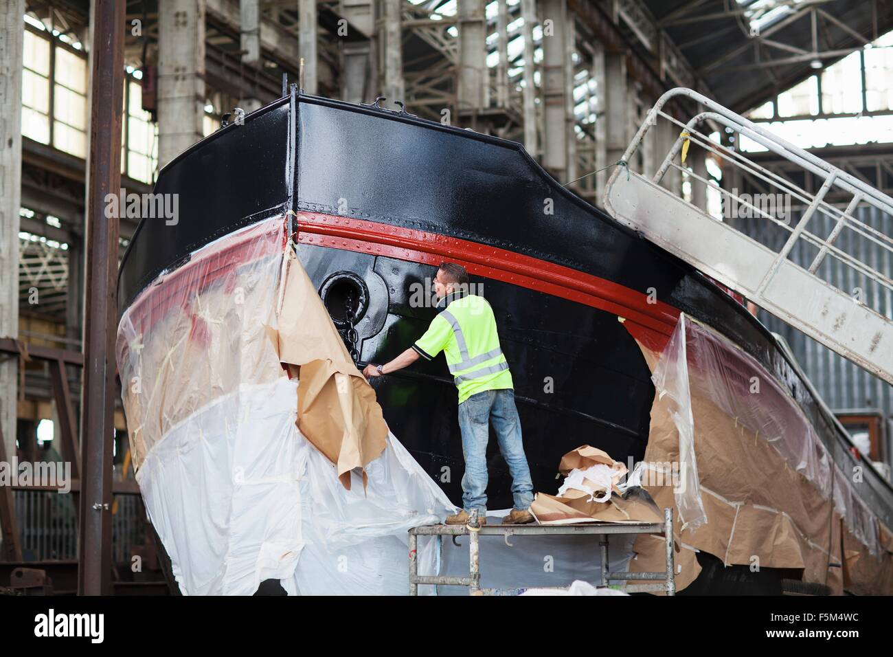 I lavoratori di unwrapping barca in cantiere Foto Stock