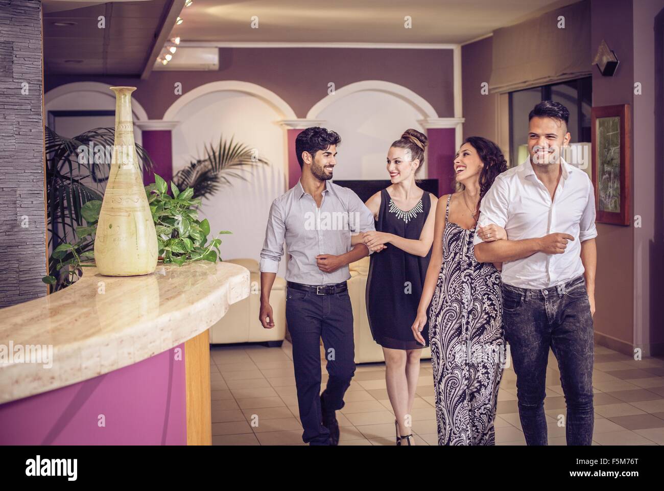 Due coppie giovani lasciando la lobby dell'hotel per la notte Foto Stock