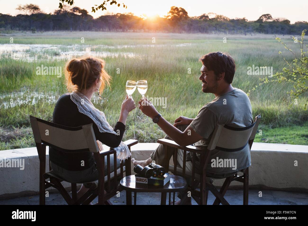 Giovane vinificazione toast al tramonto a safari lodge, Parco Nazionale di Kafue, Zambia Foto Stock