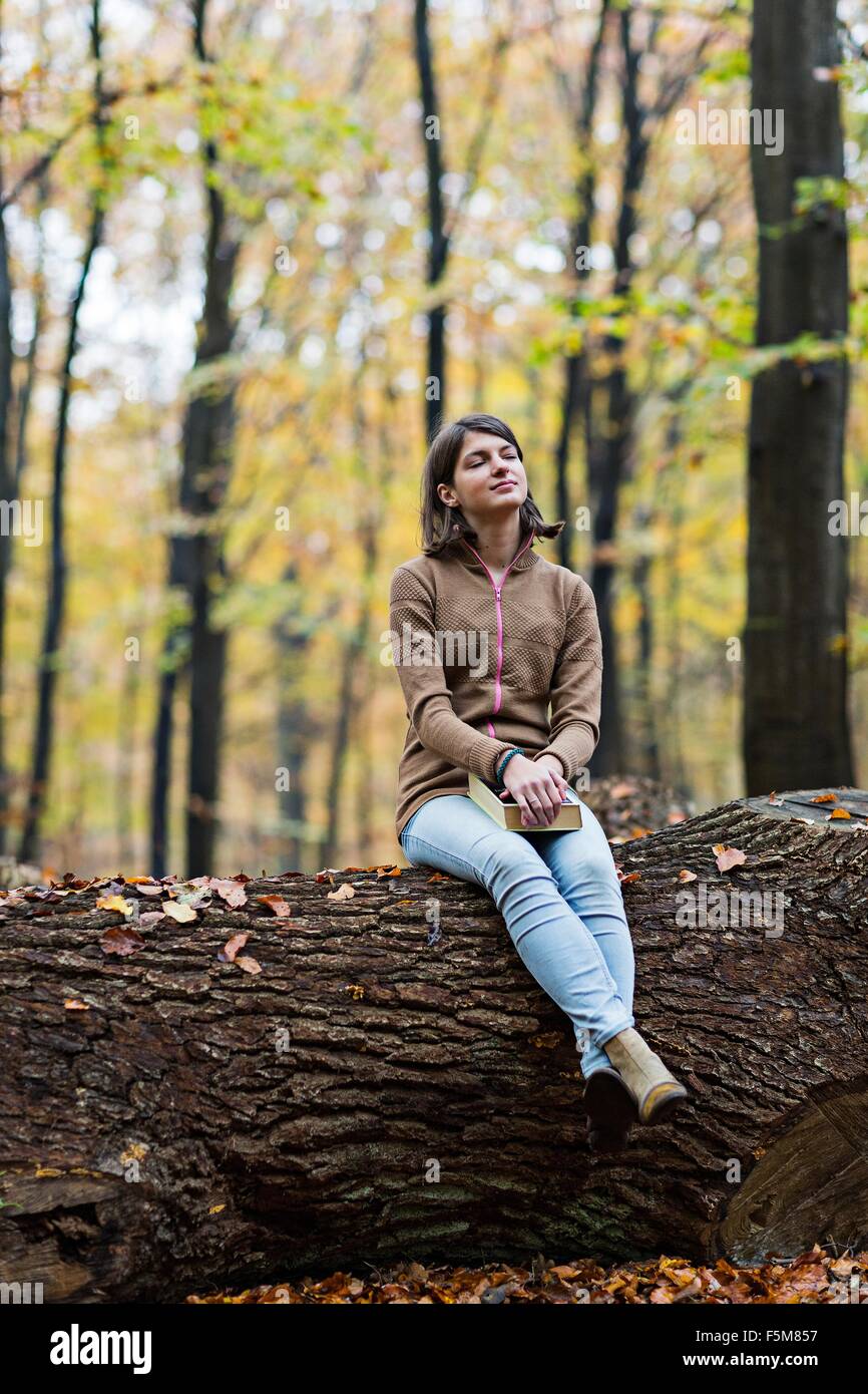 Ragazza fantasticando sul tronco di albero nella foresta di autunno Foto Stock