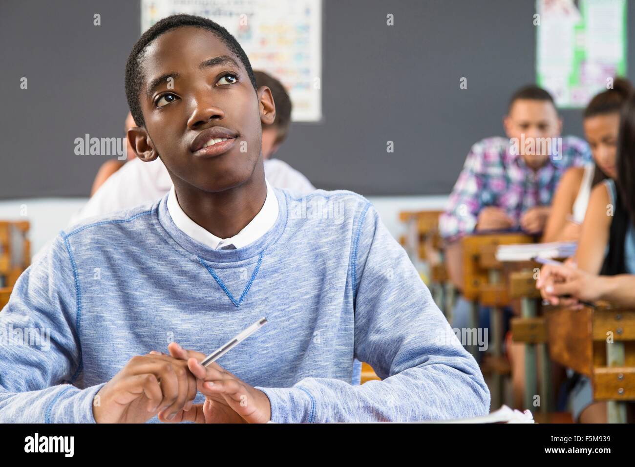Ritratto di studente maschio, seduti alla scrivania in aula Foto Stock