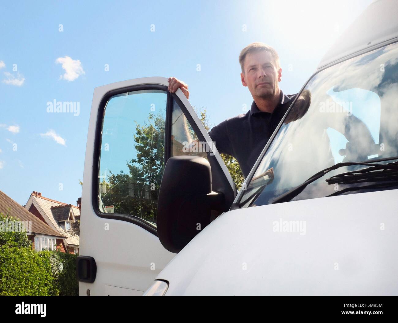 Uomo di consegna guardando fuori dal furgone bianco sulla strada suburbana Foto Stock