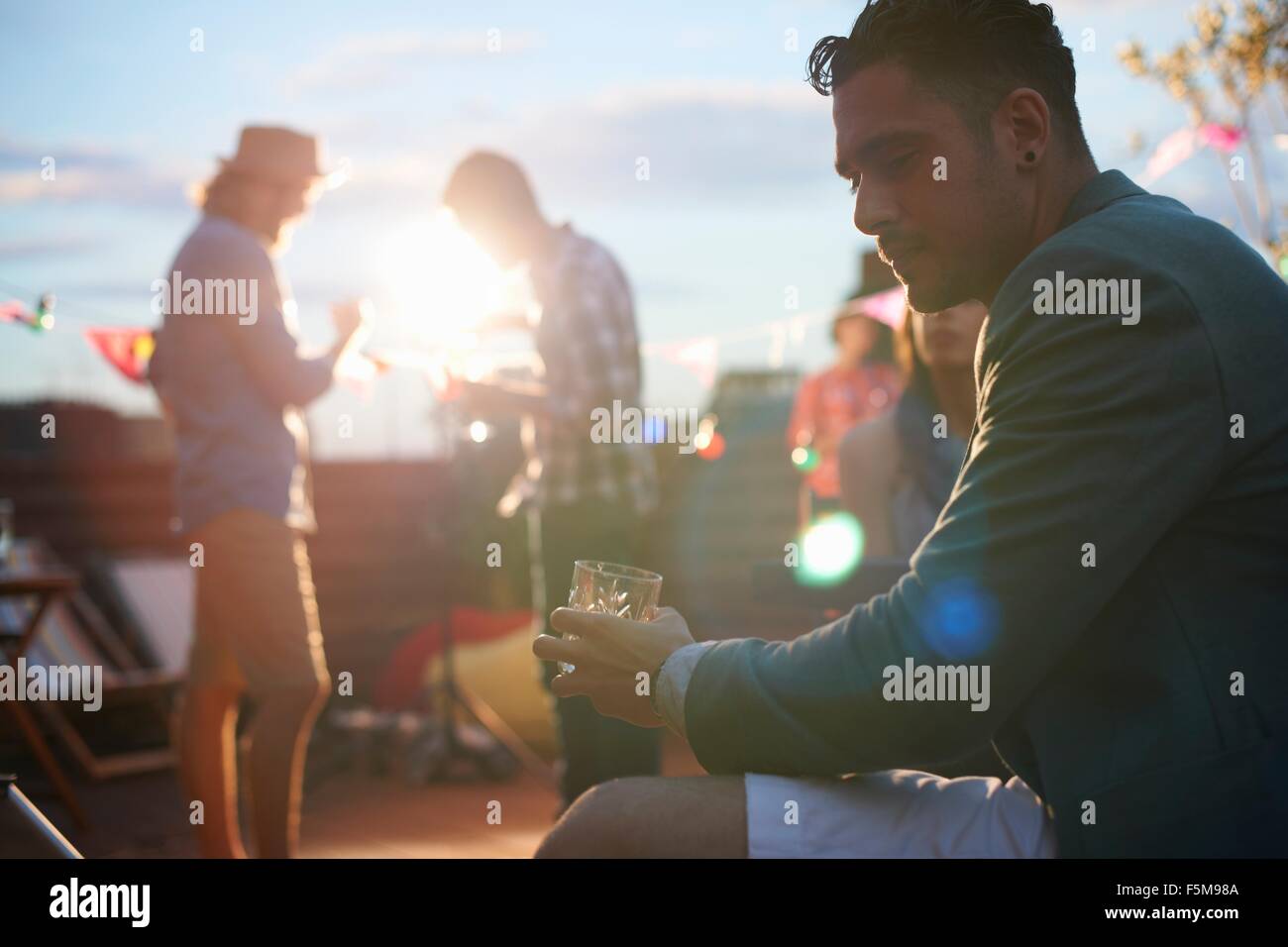 Uomo seduto da solo con drink presso la sera presto parte Foto Stock