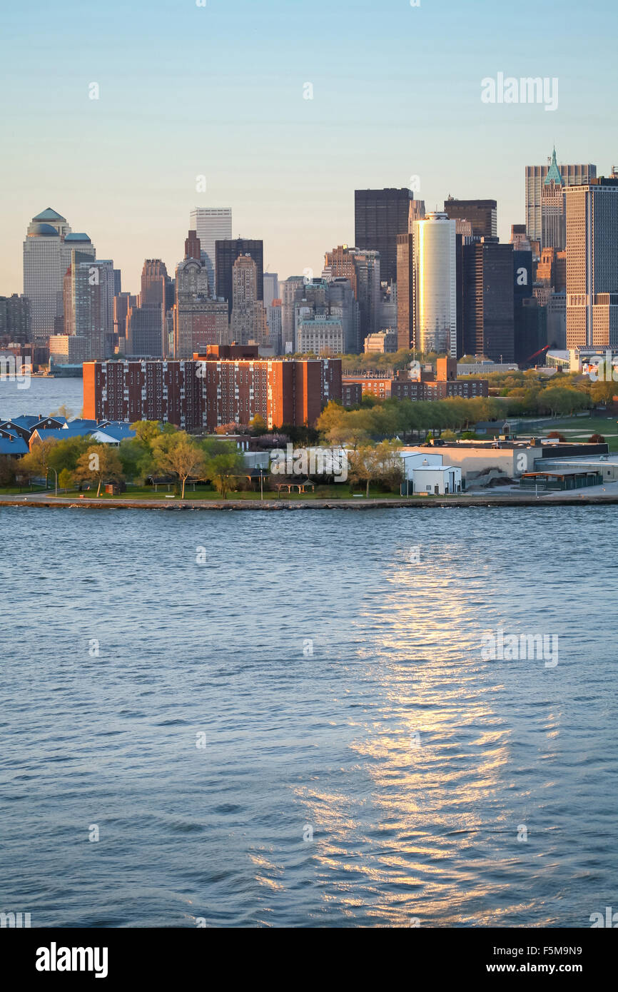Il Governors Island e il Manhattan Financial District vista dal porto di New York al tramonto nella città di New York, Stati Uniti d'America. Foto Stock